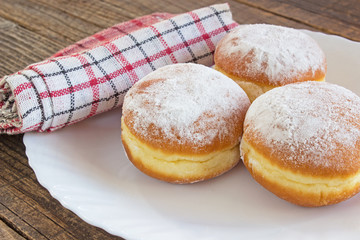 Berliner donuts in plate on wooden table