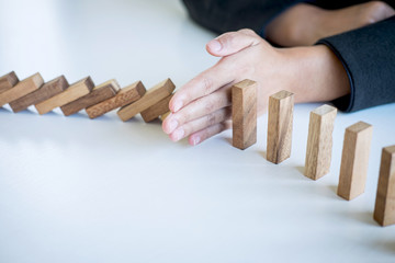 Risk and Strategy in Business, Image of hand stopping falling collapse wooden block dominoes effect...