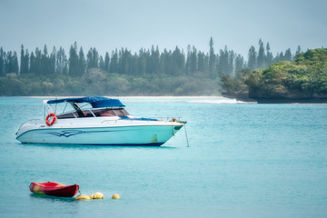 Boats on the water at Kuto Bay on a foggy morning on the Isle of Pines in New Caledonia, South Pacific Ocean.