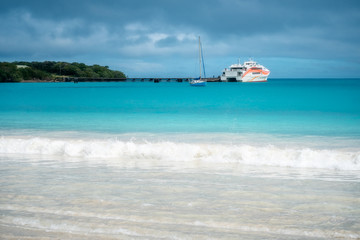 Obraz premium Pier and ferry boat at Kuto Bay on a beautiful but slightly overcast morning at Isle of Pines in New Caledonia, South Pacific Ocean.