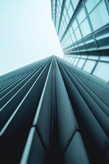 Obraz premium Abstract view of lines of a modern skyscraper building. look up view into a grey sky. Frankfurt am Main in Germany