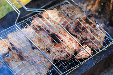 Grilled meat in barbecue with flames and coals.