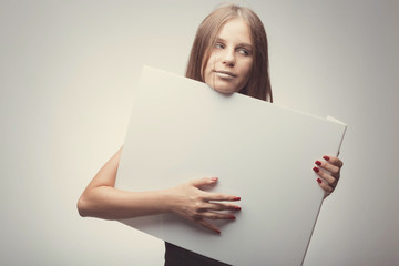 Fashion pretty girl holding white board with place for text. Surprised girl looking serious