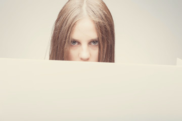 Fashion pretty girl holding white board with place for text. Surprised girl looking serious