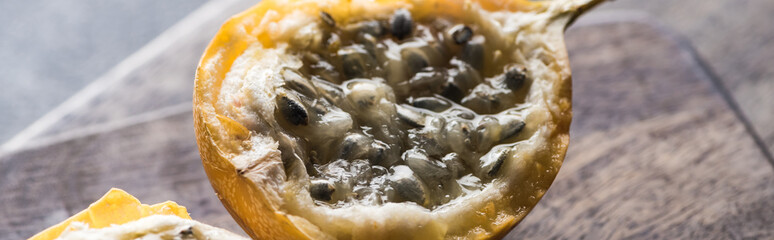 close up view of sweet granadilla on wooden cutting boards on grey background, panoramic shot
