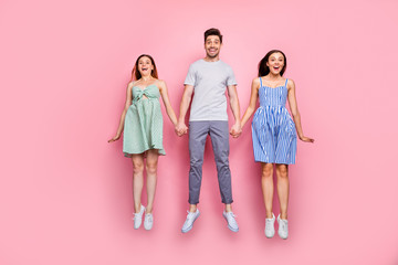 Fototapeta premium Full length photo of cheerful youngsters enjoying jumping wearing striped t-shirt pants trousers isolated over pink background