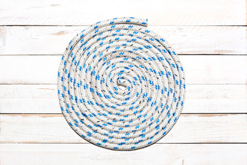 nautical rope in spiral shape on a white wooden  deck with copy space for your text