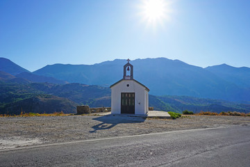 Christian white basilica chapel (church) with a bell on a mountainside on the island of Crete,...