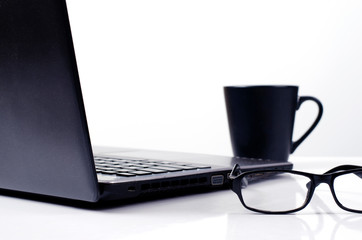 Close up of eyeglasses with labtop computer and coffee cups on white backgrounds