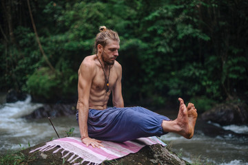 Yoga practice and meditation in nature. Man practicing near river