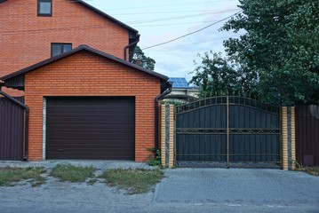 brown brick garage and wrought iron fence in the street