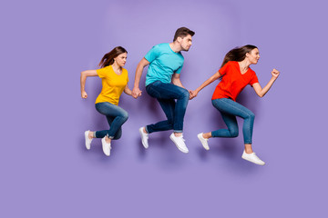 Fototapeta na wymiar Full length size body photo of concentrated with funny facial expression group of three hipsters running away do not look back isolated violet background