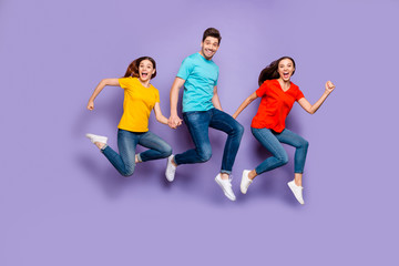 Fototapeta na wymiar Full length size body photo of three excited cheerful crazy unstoppable actively moving victorious successful freelancers group of millennials holding hands isolated violet background