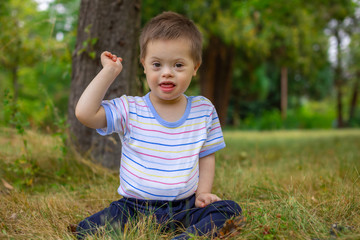 Cute small boy with Down syndrome playing in summer day on nature