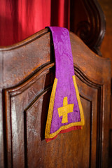 purple stole of a priest resting on a confessional