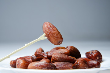 Dates on a plate and chopstick for dates. Bright saturated colors. Good fruit texture.