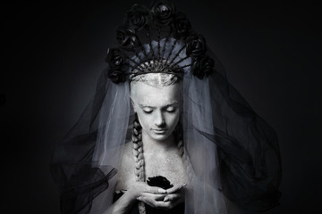 Artistic portrait of a girl covered in cracked white paint. Halloween makeup.