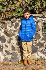 Boy stands out looking into the ground while exhibiting an autumn fashion wear for kids. Autumn...