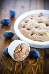 sweet cooked sponge cake with plums, on a table.