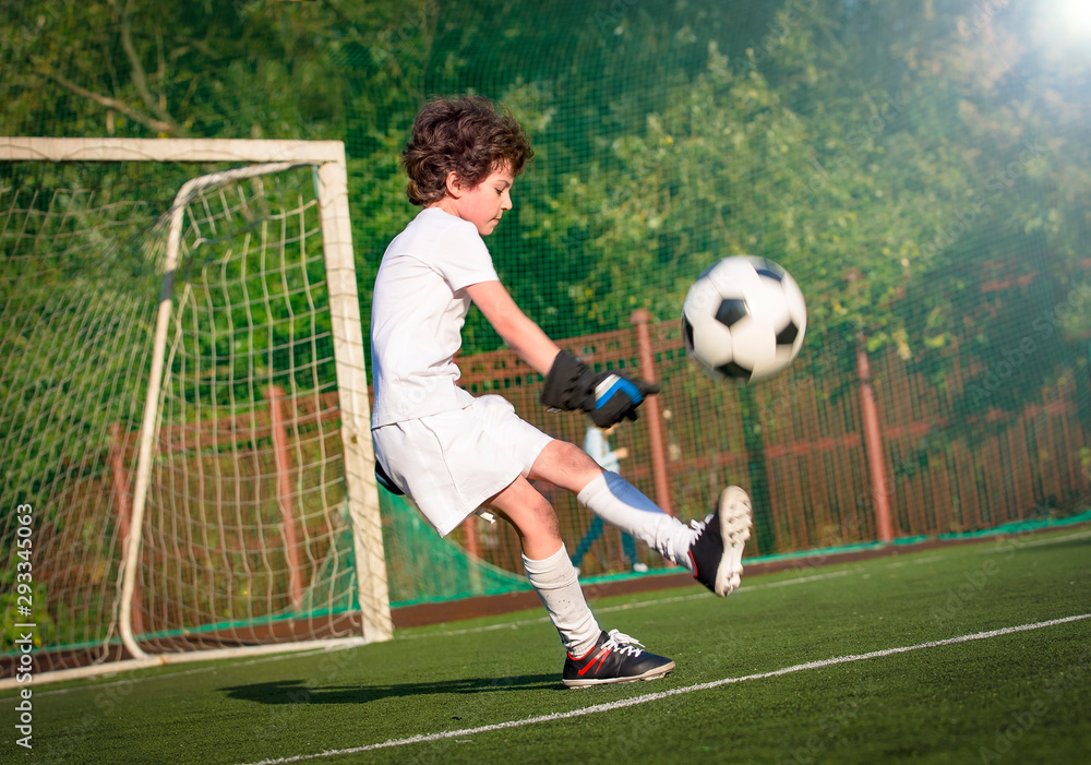 Wall mural Boys in white sportswear running on soccer field. Young footballers dribble and kick football ball in game. Training, active lifestyle, sport, children activity concept. selective focus