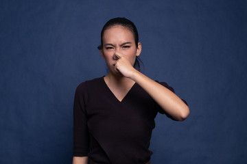 Young Asian woman  holding her nose because of a bad smell.