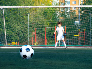 Young goalkeeper on an outdoor court standing in the football gate. Football, soccer player. Goalkeeper waits to catch the ball.selective focus