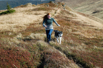 Girl runs with dog. The Husky are black and white. Hiking in the mountains. Carpathian Mountains
