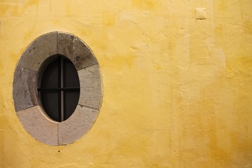 Medieval oval window isolated in a yellow wall background (Madeira, Portugal)