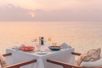 Romantic dinner on the beach. Wine glasses next to a beautiful dinner table setting, luxury resort...