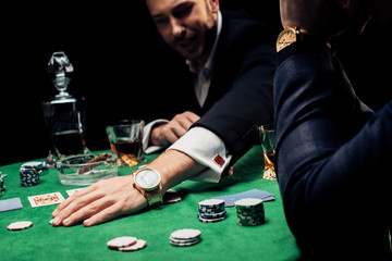 selective focus of man touching poker chips isolated on black