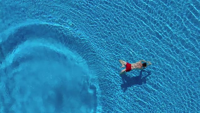 View from the top as a man dives into the pool and swims under the water