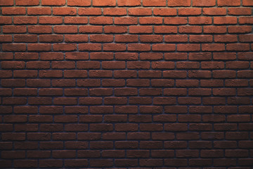 An orange brick wall with light gradient. Gradient stone background with low light and copy space. Place for advert.