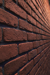 An orange brick wall at an angle with bokeh. Stone blurred background. Closeup vertical photo.