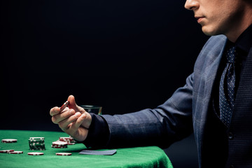 cropped view of man holding poker chip isolated on black