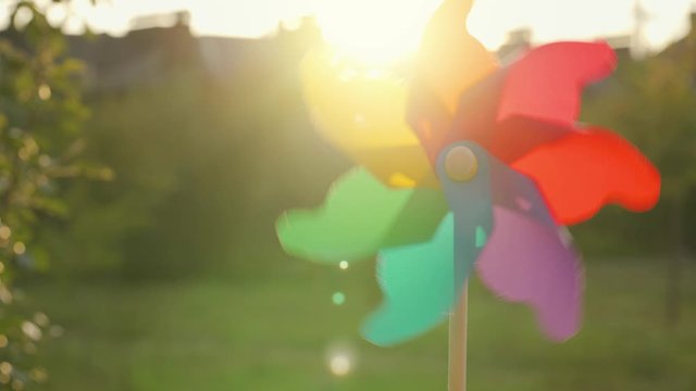 Plastic rainbow windmill rotates against the setting sun