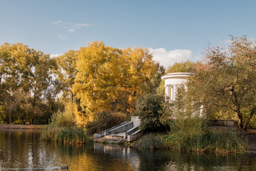 Fototapeta na wymiar Old park in fall. View of lake and white rotunda.