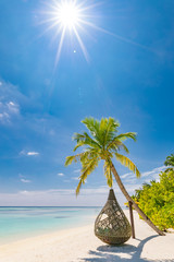 Beautiful tropical Maldives beach under cloudy sky with swings or hammock on coconut palm. Luxury vacation concept