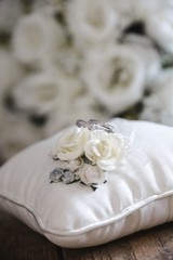  silver wedding rings on a white silk pillow with roses  with roses in the background