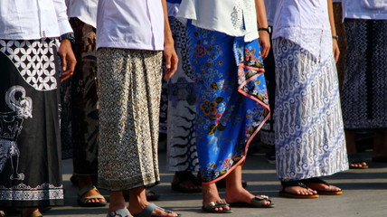 Various motifs of batik sarongs, which are being hit by a group of men and women - obrazy, fototapety, plakaty