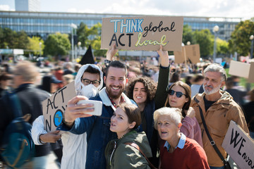 People with placards and posters on global strike for climate change, taking selfie.