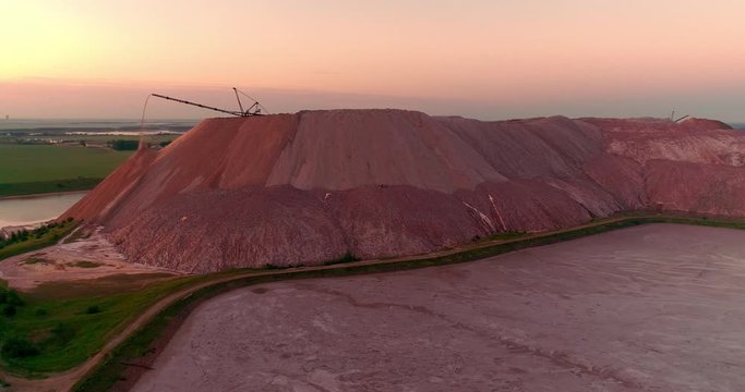Mountains tailing piles and water basins. Waste left after potash salt ore extraction from underground mines falling from the conveyor belt. Environmental pollution from industrial production.