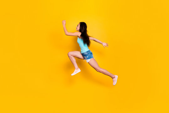 Full length body size photo of side profile sports woman in urgency running after sales and discounted goods wearing jeans denim shorts sportive sneakers isolated vibrant color background