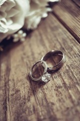 Beautiful toned picture with wedding rings lie on a wooden surface against the background of a...