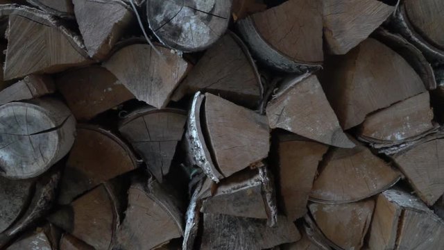 Dry chopped firewood logs stacked in a large woodpile. Firewood for the fireplace, dolly shot, camera slide.