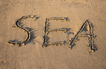 ord SEA drawn on the sand  at the beach at sunset