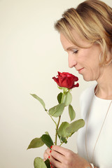 frau riecht an Rose verliebt happy