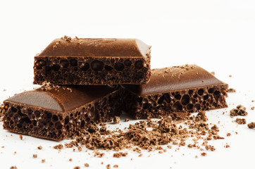 Slices of aerated chocolate and chocolate crumb on a white background