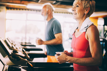 Senior people running in machine treadmill at fitness gym club