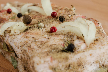A piece of bacon with different types of pepper and salt on the board