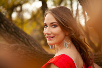 beauty young caucasian woman in red dress walking in the fall park alone and enjoy happy